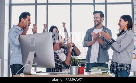 Creative director team applause for good solution of project with designer at meeting table with desktop computer.discussion idea in creative office Stock Photo