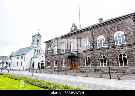 Reykjavik, Iceland - June 19, 2018: Cathedral church in downtown capital city street at Austurvollur Kirkjustaeti with Althingi Parliament House stone Stock Photo