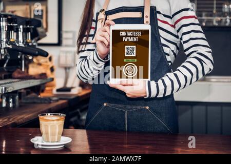 CLose up woman barista hand holding tablet with contactless payment method at counter bar in restaurant cafe.online payment Stock Photo