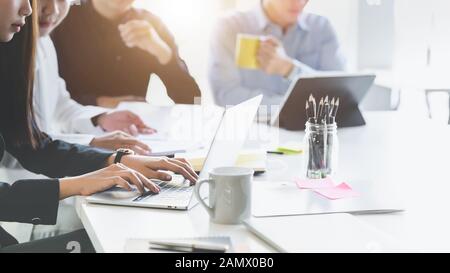 Cropped shot of business group concentrating on their project while siting in simple meeting room with office supplies Stock Photo