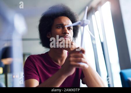 Focused African man looking at model of wind turbine Stock Photo