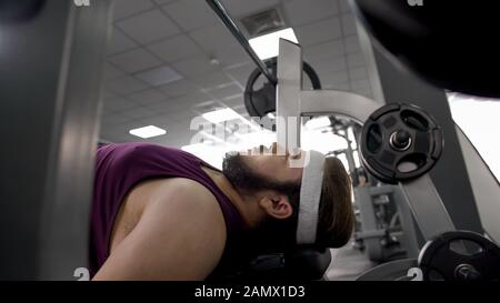 Purposeful obese man lying on bench, mental training before barbell lifting Stock Photo