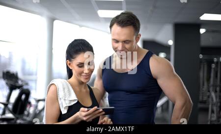 Woman with trainer checking amount of burned calories in smartphone application Stock Photo