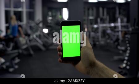 Sportsman checking online smartphone application, monitoring pulse, green screen Stock Photo