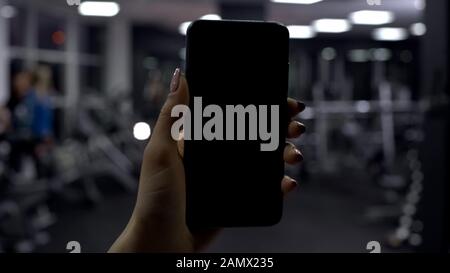 Woman checking amount of burned calories in smartphone application, black screen Stock Photo