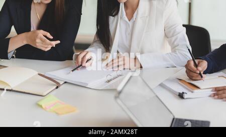 Cropped shot of two of businesswoman discussing on their project while sitting in simple co working space with office supplies Stock Photo