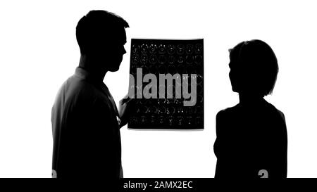 Silhouettes of young doctor showing bad mri results to female patient, treatment Stock Photo