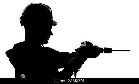 Construction worker silhouette in protective helmet using drill for repairs Stock Photo