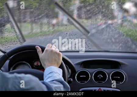 A vehicle drives on a wet road at sunrise or sunset, with the sun ...