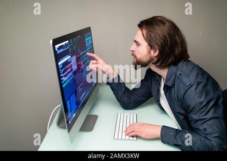 Male programmer working on desktop computer at white desk in office. Stock Photo