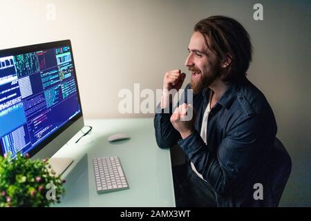 Glad man programer working on computer with win gesture Stock Photo