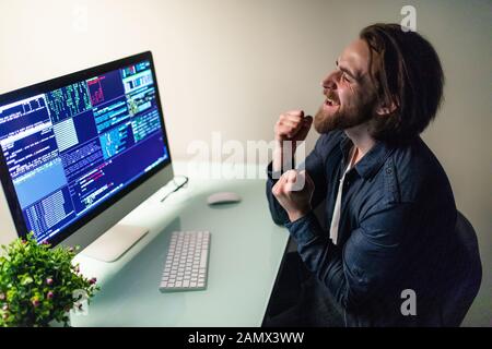 Glad man programer working on computer with win gesture Stock Photo