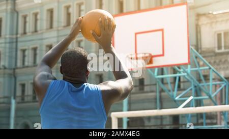 Skilled Afro-American person throwing ball into basket, active sports hobby