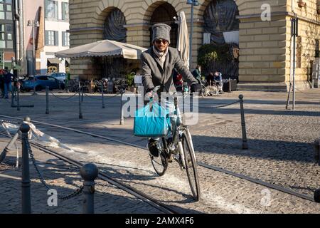 Milan, Italy - January 11, 2020: A very stylish Deliveroo courier on bike deliver tasty food in a city centre street. City Food delivery service. Onli Stock Photo