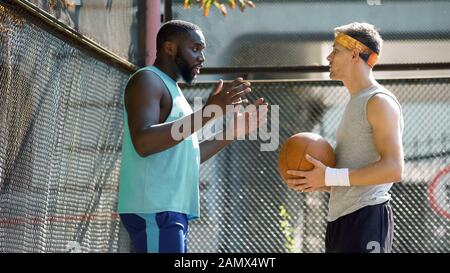 Two athletic basketball players arguing about game score at stadium, sport Stock Photo