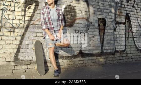 Male with headset standing near graffiti wall, listening to music, holidays Stock Photo