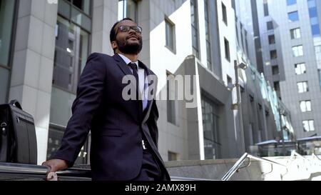 Afro-American employee standing on stairs near office building, prospects Stock Photo