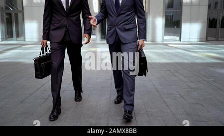 Business people walking out office building discussing joint project mutual work Stock Photo