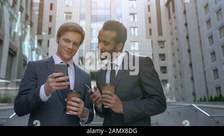 Two multiracial coworkers having coffee break, surfing social networks, lunch Stock Photo