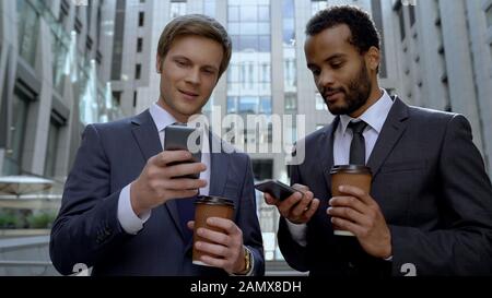Colleagues scrolling smartphones on coffee break, not talking to each other Stock Photo