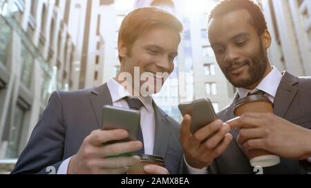 Multiracial colleagues looking photos at coffee break using smartphone apps Stock Photo