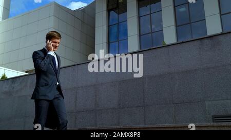 Happy young businessman talking on phone, receiving good news, successful deal Stock Photo