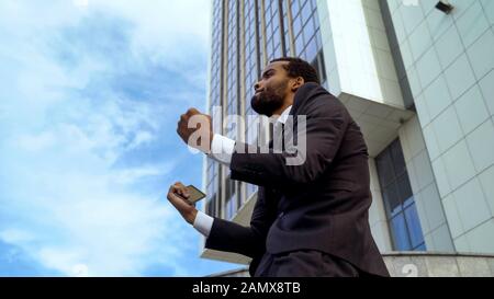 Afro-american office worker happy about good news, promotion, successful startup Stock Photo