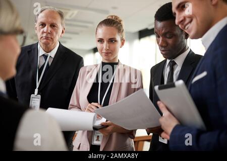Group of journalists holding papers and tablet pc standing and listening to businesswoman Stock Photo