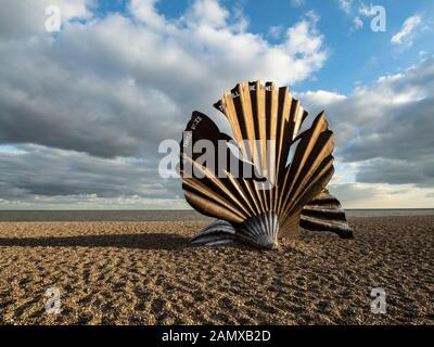 A view of the shell sculpture on Aldeburgh beach in bright sunlight with clouds in the sky.