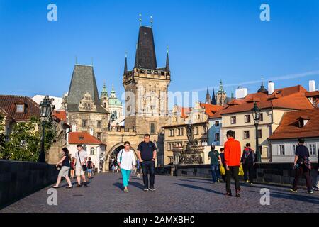 PRAGUE, CZECH REPUBLIC - SEPTEMBER 20 2018: Tourist walking on the Charles Bridge with Town Bridge Tower in background on September 20, 2018 in Prague