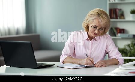 Business woman writing down to notebook plan for near future, freelancer work Stock Photo