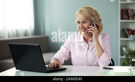 Businesswoman in her 50 calling children during break at work, communication Stock Photo