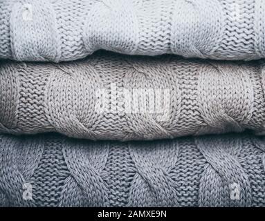 Closeup on folded soft knitware sweaters, pastel grey colors Stock Photo