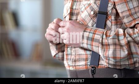 Adult man buttoning up checkered shirt, vintage retro style dresses, side view Stock Photo