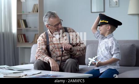 Happy boy playing with toy airplane, grandfather former pilot proud of grandson Stock Photo