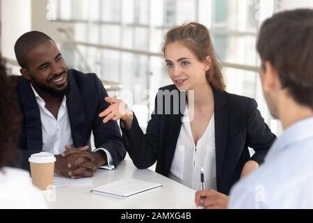 Female employee talk discussing ideas with colleagues at meeting Stock Photo