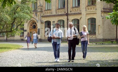 Group of multi-ethnic students and teacher discussing project, walking in park Stock Photo