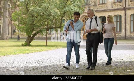 Mixed-race students and teacher walking in park and talking, higher education Stock Photo