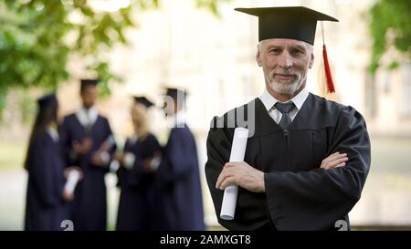 Confident man in graduation outfit, male obtaining degree, academic career Stock Photo