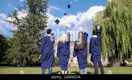 Graduate students throwing square hats up, popular tradition, higher education Stock Photo