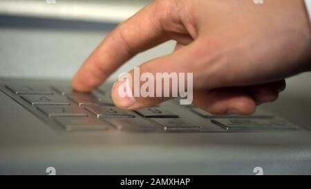 Male hand using ATM, inserting unique personal code and pressing buttons Stock Photo