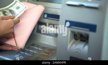 Womans hands putting dollars in wallet, cash withdrawn from ATM, travelling Stock Photo