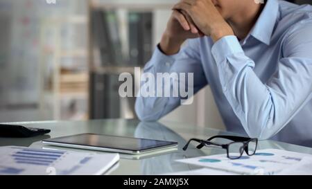 Pensive businessman using tablet, counting calculator, small business income Stock Photo