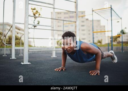 Fit young african american man working out on crossfit strength training doing push ups at the calisthenics park Stock Photo