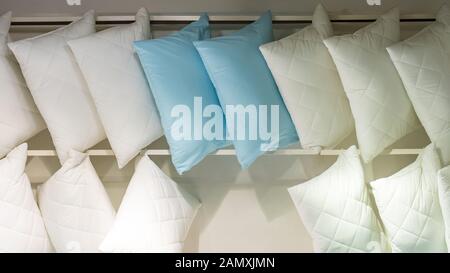 White blue lots of pillows on a store shelf. Bedding, comfortable quilted pillow for sleeping. Soft cotton natural fabric material Stock Photo