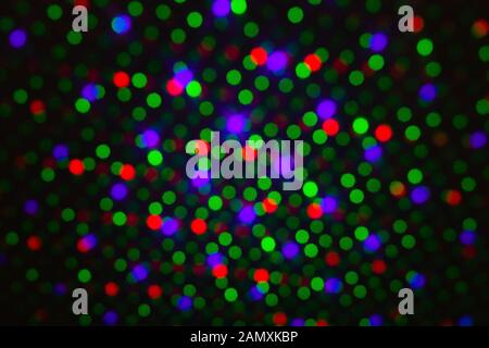 Abstract dot defocus background backdrop, rainbow colored green red violet round glitter on black background. Illumination blurry lights, abstract Stock Photo