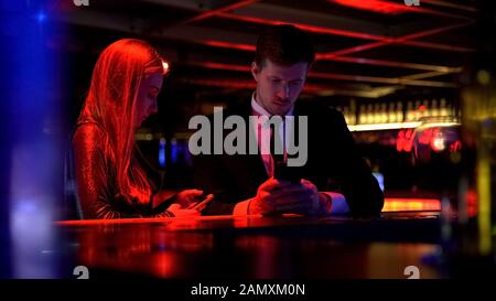 Gadget addicted couple using their smart phone in bar, lack of communication Stock Photo