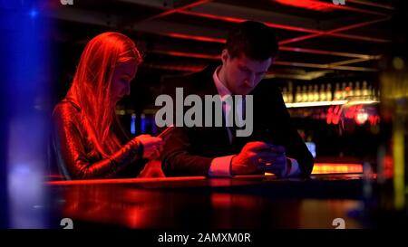 Young people surfing web in bar, lack of communication, smartphone addiction Stock Photo