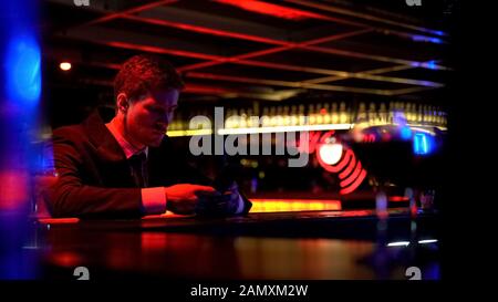 Lonely man bored at bar counter, browsing social media, lack of communication Stock Photo