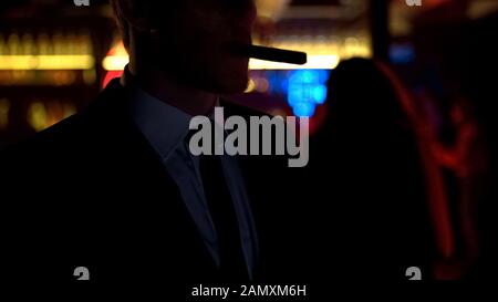 Drunk businessman smoking cigar in elite bar in evening after hard workday Stock Photo